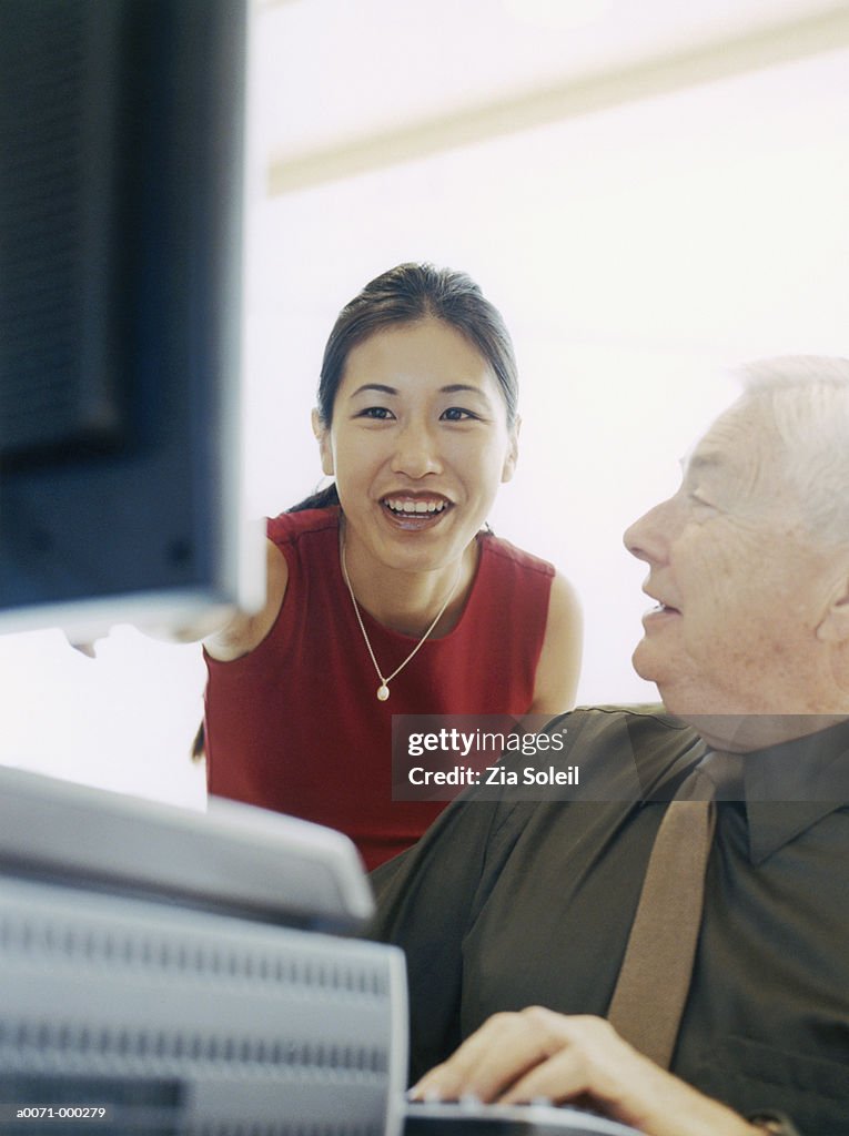 Woman Tutoring Man on Computer