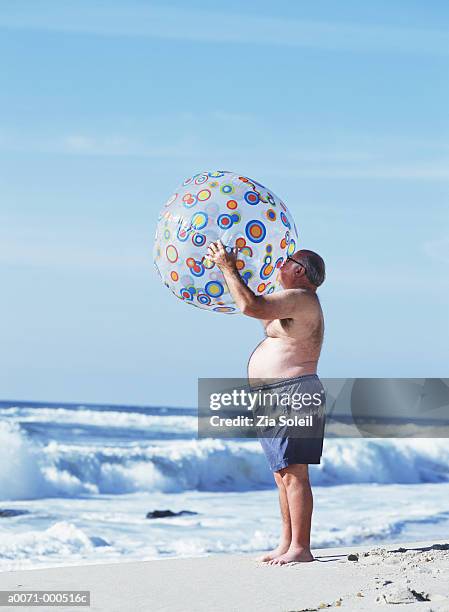 man inflating beach ball - man with big balls stock pictures, royalty-free photos & images