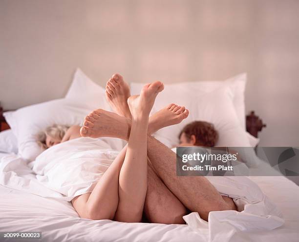 couple in bed feet entwined - man touching womans leg fotografías e imágenes de stock