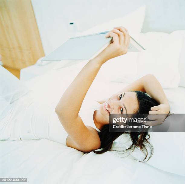 woman on bed with book - zurücklehnen stock-fotos und bilder