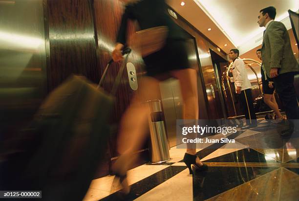 woman pulling wheeled suitcase - hotel page stock-fotos und bilder