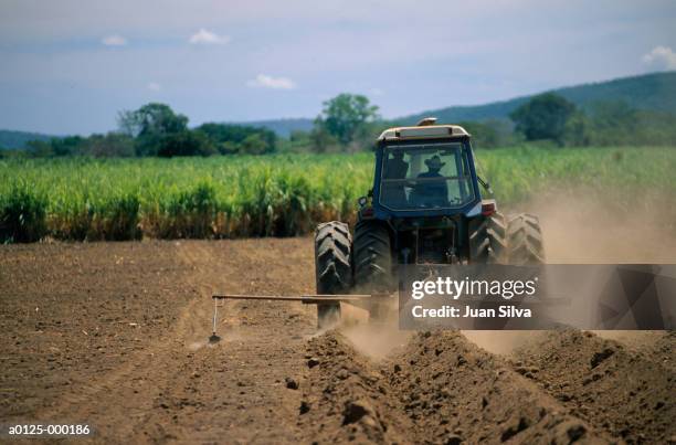 tractor plowing soil - trekker stockfoto's en -beelden