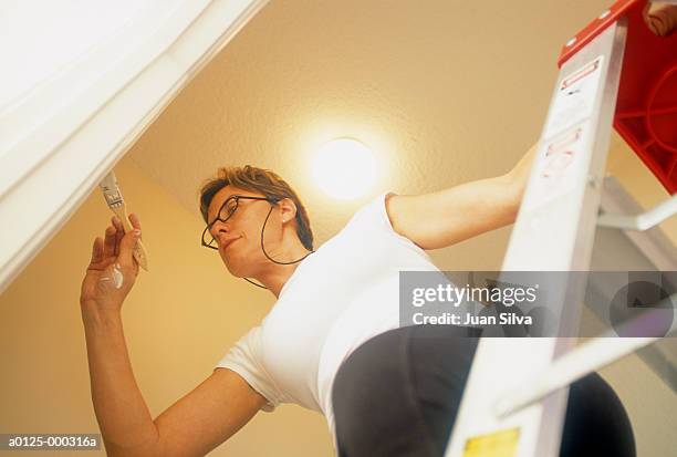 woman on stepladder painting - woman on ladder painting stock pictures, royalty-free photos & images