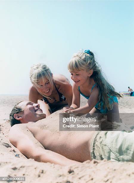 family on beach - burying stockfoto's en -beelden