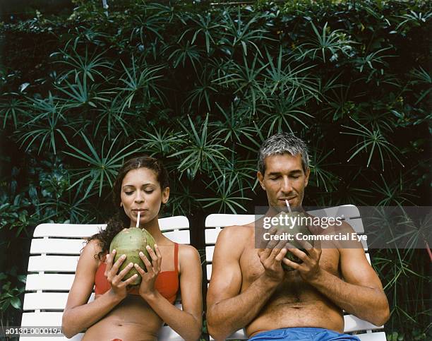 couple drinking from coconuts - 2 coconut drinks ストックフォトと画像