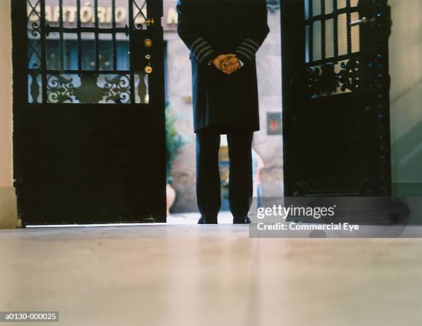 door attendant stands by doors - doorman stockfoto's en -beelden