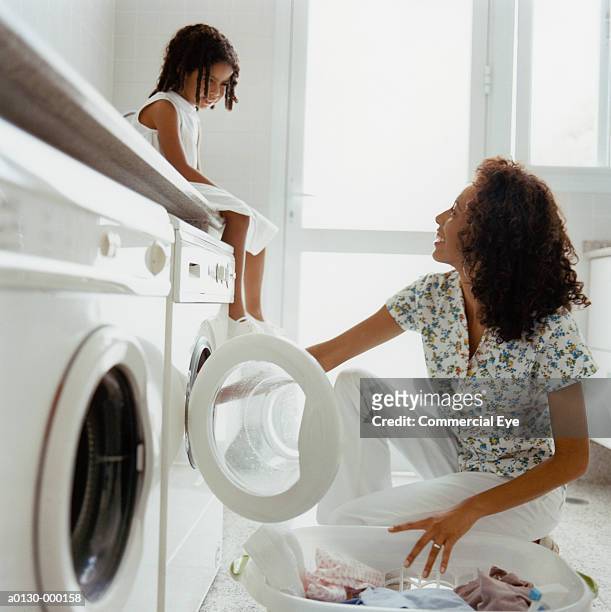 girl watches mum doing laundry - waschen stock-fotos und bilder