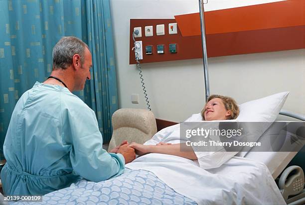 surgeon talking to patient - man and woman holding hands profile stock-fotos und bilder