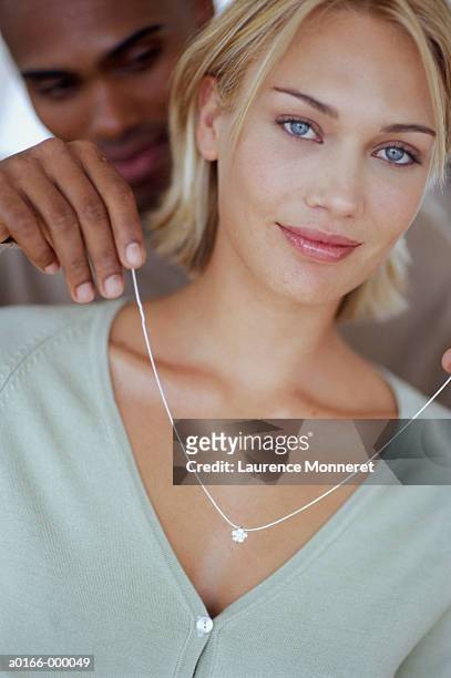 man placing necklace on woman - collana foto e immagini stock