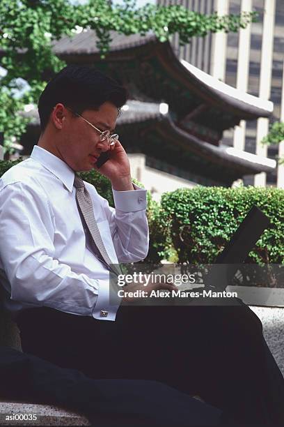 male executive with laptop computer and cellular phone in seoul, korea - seoul province stockfoto's en -beelden