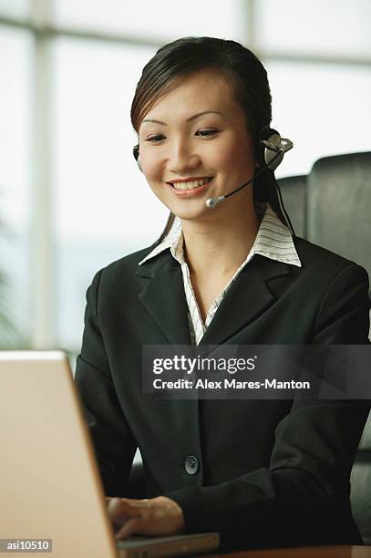 young woman using laptop and wearing hands-free device - duty free 個照片及圖片檔