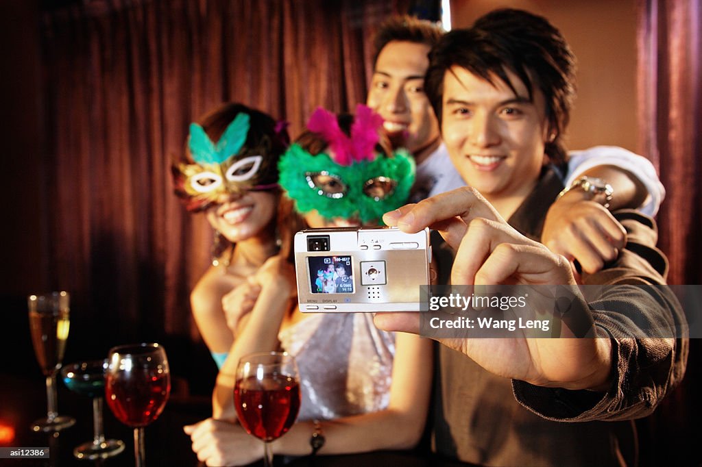 Couples with masks taking a picture with camera