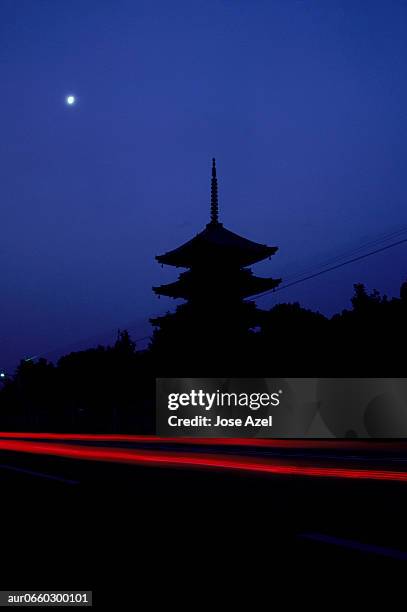 silhouette of a temple and the red streak of a passing car, japan. (motion blur) - passer ストックフォトと画像