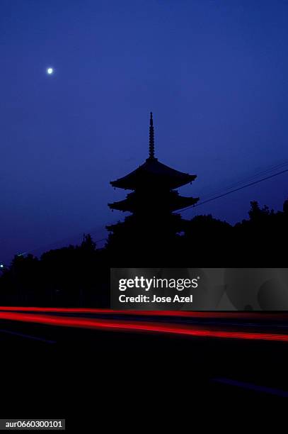 silhouette of a temple and the red streak of a passing car, japan. (motion blur) - japanese pagoda bildbanksfoton och bilder