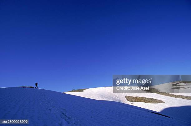 a distant view of a man walking amidst snowy hillside, wyoming, usa. - distant imagens e fotografias de stock