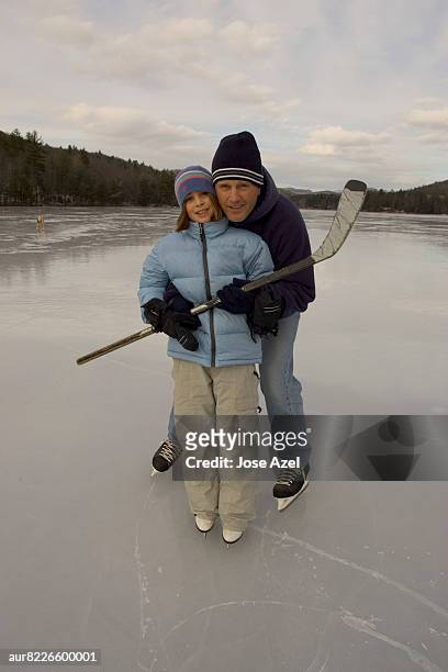 father daughter looking at camera while standing on frozen pond, new england, usa - pond hockey stock-fotos und bilder