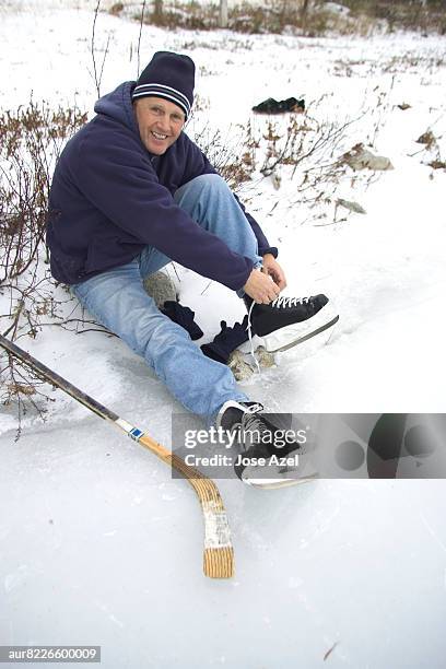 man tieing shoe lace on frozen lake, new england, usa - new england   usa stock pictures, royalty-free photos & images