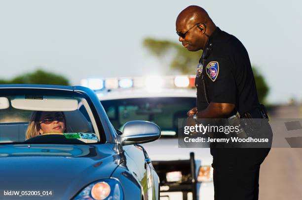 police officer talking to a mid adult woman sitting in a car - パトカー　ミラー ストックフォトと画像