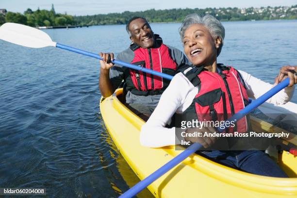 elderly couple sitting together in a kayak on a lake - kayak imagens e fotografias de stock