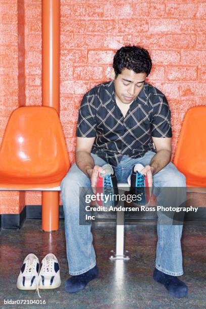 young man sitting holding bowling shoes - bowling shoe stock pictures, royalty-free photos & images