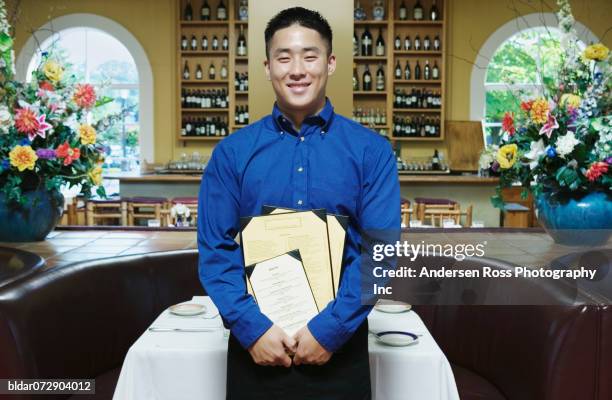 portrait of a waiter standing holding a menu in a restaurant - cafe symmetry stock pictures, royalty-free photos & images