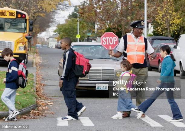 crossing guard helping kids cross safely - cross road children stock-fotos und bilder