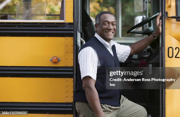 school bus driver standing by bus - busfahrer stock-fotos und bilder