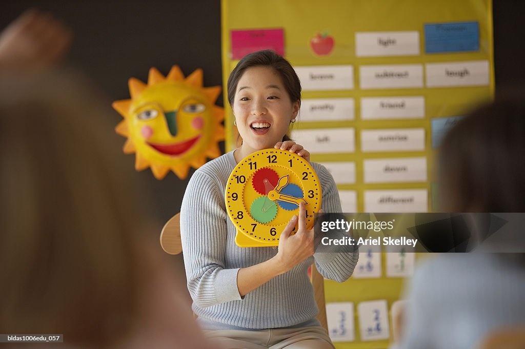 Female teacher showing a clock to the students in a classroom