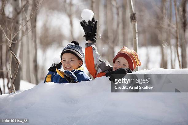 two boys throwing snowballs - bola de neve imagens e fotografias de stock