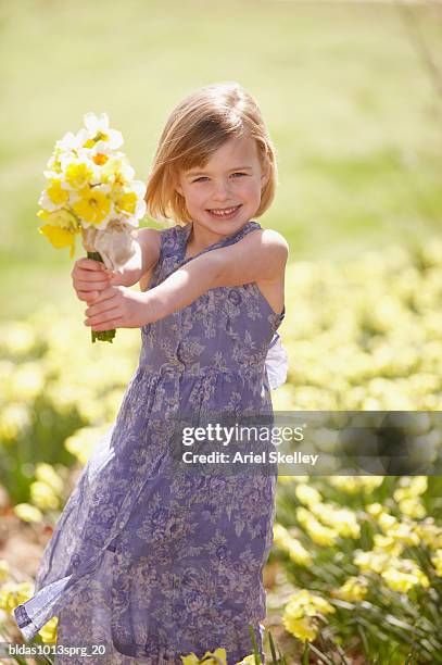 portrait of a girl holding a bouquet of flowers in a field - ariel skelley stock pictures, royalty-free photos & images