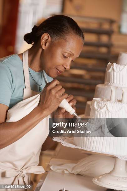 side profile of a mature woman icing a cake - ariel skelley stock-fotos und bilder