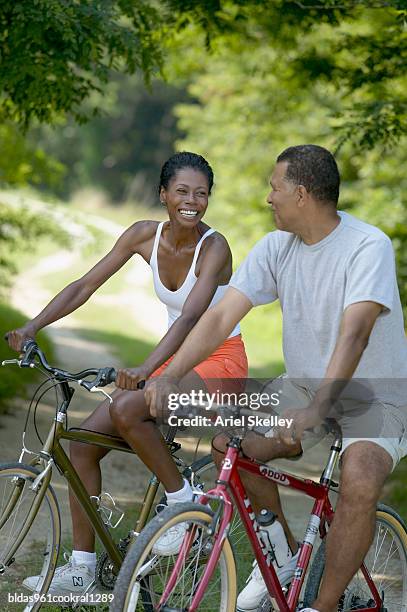 mid adult couple riding bicycles - ariel skelley stock pictures, royalty-free photos & images