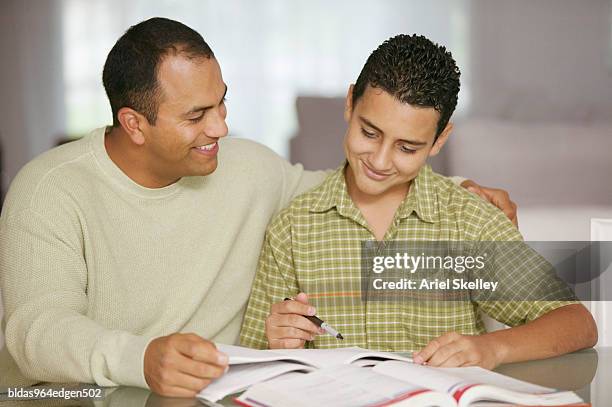 mid adult man sitting and teaching his son - ariel skelley stock pictures, royalty-free photos & images