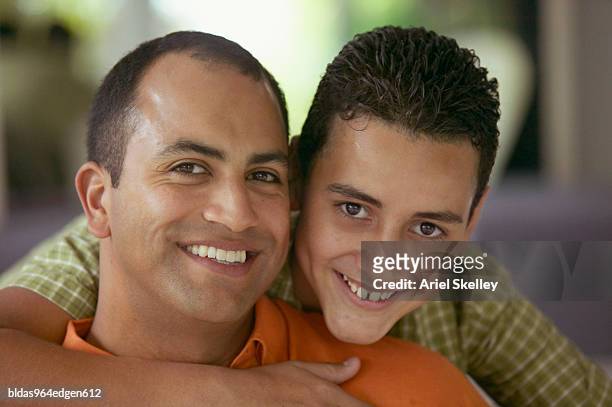 portrait of a teenage boy hugging a young man - ariel skelley stock pictures, royalty-free photos & images