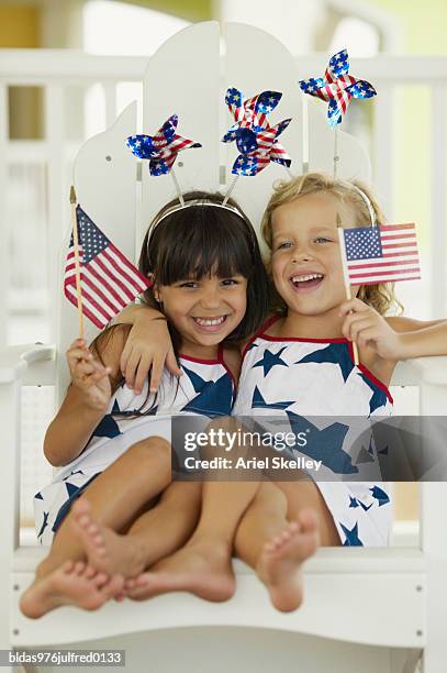 two young girls sitting holding flags in their hands - ariel skelley stock pictures, royalty-free photos & images