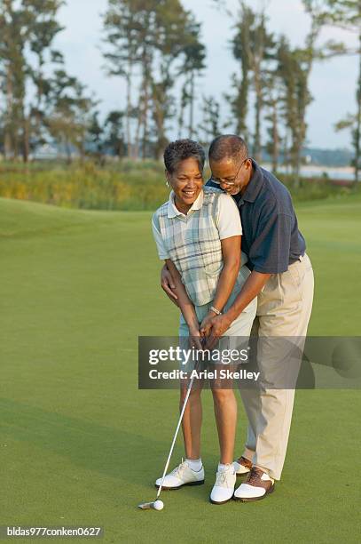 mature man teaching a mature woman how to play golf - how fotografías e imágenes de stock