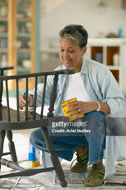 mature woman painting a chair - ariel skelley stock pictures, royalty-free photos & images