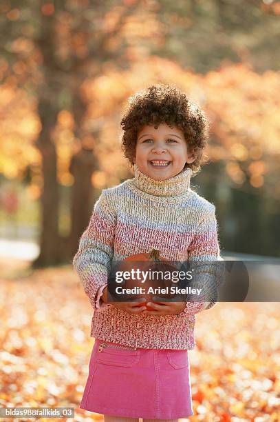 girl holding a pumpkin smiling - ariel skelley stock pictures, royalty-free photos & images