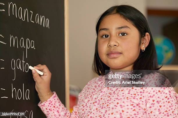 portrait of a girl writing with a chalk on a blackboard - ariel skelley stock pictures, royalty-free photos & images