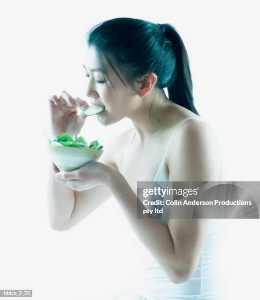 side profile of a young woman eating salad - side salad stock pictures, royalty-free photos & images