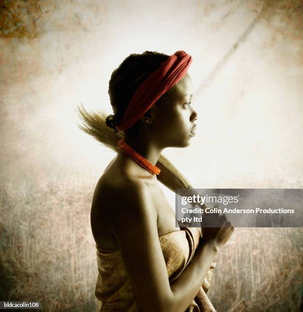 side profile of a young tribal woman holding an artifact on her shoulder - african tribal culture stock-fotos und bilder