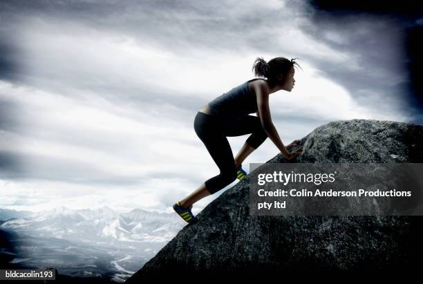 young woman climbing up a rock face - women rock climbing stock pictures, royalty-free photos & images