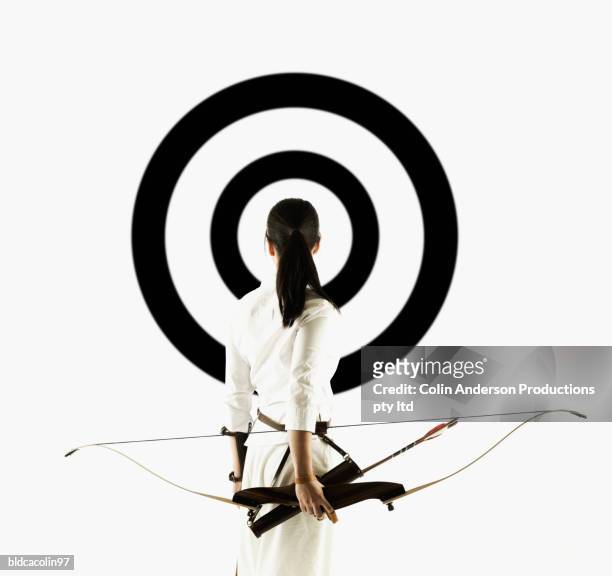 rear view of a young woman holding a crossbow looking at a target - crossbow ストックフォトと画像