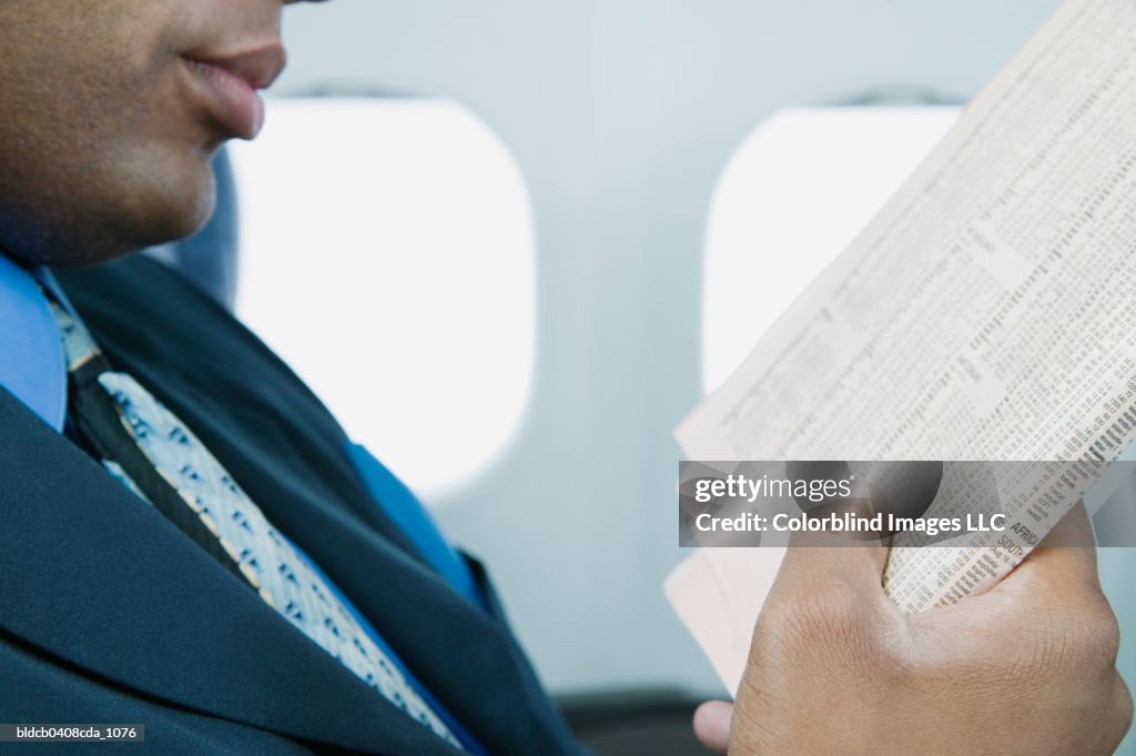 Businessman sitting in an airplane reading a newspaper