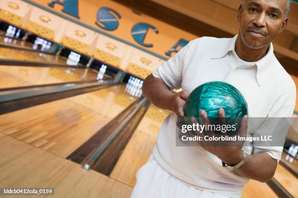 portrait of a mature man holding a bowling ball in a bowling alley - black alley stock pictures, royalty-free photos & images