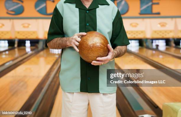 mid section view of a mid adult man holding a bowling ball in a bowling alley - ten pin bowling foto e immagini stock