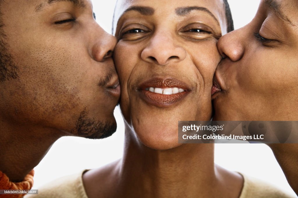Close-up of a mid adult woman being kissed by a young man and a young woman