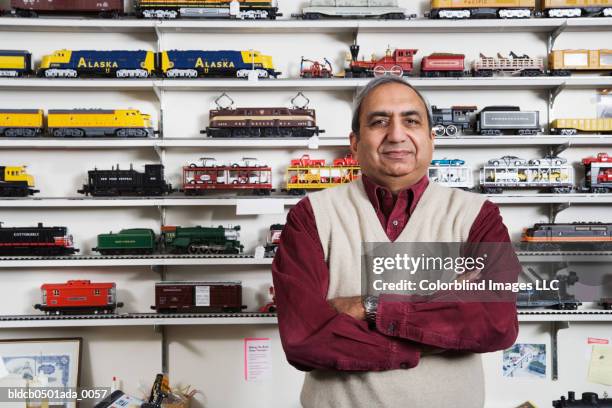 portrait of a male sales clerk standing with his arms crossed in a toy store - tank top stock pictures, royalty-free photos & images