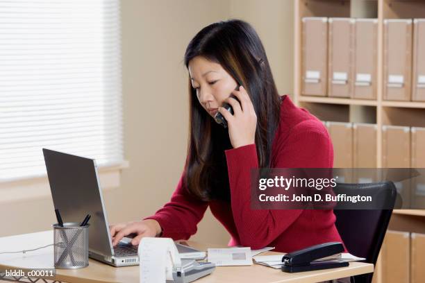 side profile of a businesswoman using a laptop in an office - staples office stockfoto's en -beelden