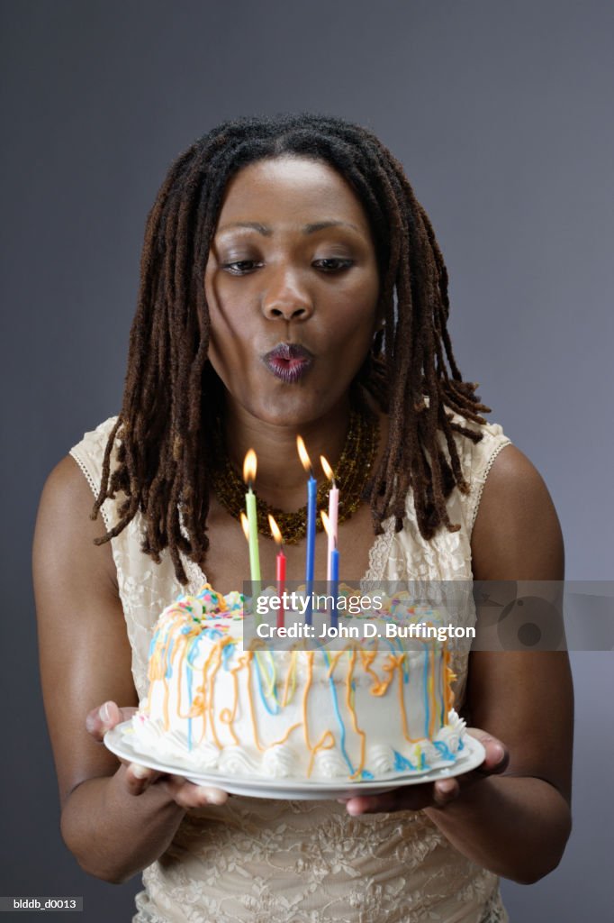 Close-up of a young woman blowing out candles on a birthday cake